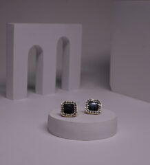 Black square stud earrings with pearl bead halo border in gold-toned frame, displayed as a pair on a white prop against a grey background.