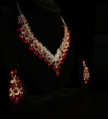 Rose gold ruby red crystal floral necklace and chandelier earring bridal jewellery set displayed on black velvet bust