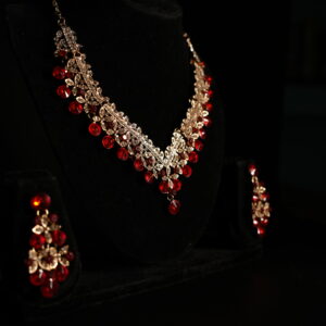 Rose gold ruby red crystal floral necklace and chandelier earring bridal jewellery set displayed on black velvet bust