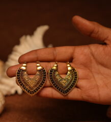 Pair of antique gold-tone filigree chandelier earrings with black crystal embellishments held in an open palm, featuring intricate scroll motifs and beaded border detail.