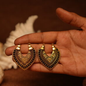 Pair of antique gold-tone filigree chandelier earrings with black crystal embellishments held in an open palm, featuring intricate scroll motifs and beaded border detail.