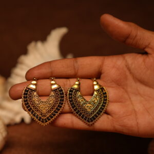 Pair of antique gold-tone filigree chandelier earrings with black crystal embellishments held in an open palm, featuring intricate scroll motifs and beaded border detail.
