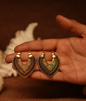 Pair of antique gold-tone filigree chandelier earrings with black crystal embellishments held in an open palm, featuring intricate scroll motifs and beaded border detail.