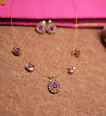 Kundan invisible wire necklace with floating purple gemstone and pearl pendants displayed on pink silk fabric with matching earrings
