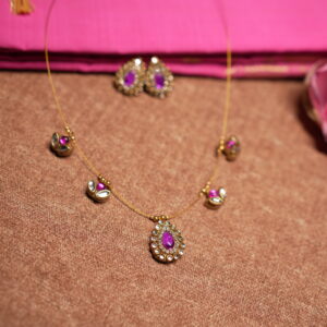 Kundan invisible wire necklace with floating purple gemstone and pearl pendants displayed on pink silk fabric with matching earrings