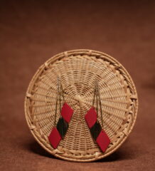 Red and green diamond shape layered drop earrings with long gold crystal chain tassel, displayed on a round wicker basket with warm brown background