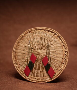 Red and green diamond shape layered drop earrings with long gold crystal chain tassel, displayed on a round wicker basket with warm brown background