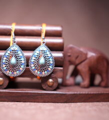Bohemian teardrop dangle earrings with silver-tone filigree, multicolour enamel mosaic tiles in blue coral and pink, and a turquoise cabochon centre stone, displayed on a wooden jewellery stand