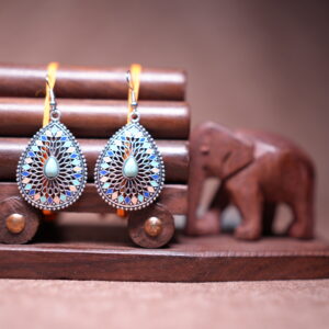 Bohemian teardrop dangle earrings with silver-tone filigree, multicolour enamel mosaic tiles in blue coral and pink, and a turquoise cabochon centre stone, displayed on a wooden jewellery stand