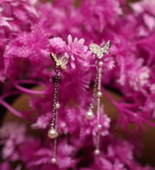 Crystal butterfly stud earrings with silver chain and faux pearl drops displayed on pink artificial flower tree – D2Dazzle fashion jewellery India