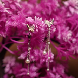 Crystal butterfly stud earrings with silver chain and faux pearl drops displayed on pink artificial flower tree – D2Dazzle fashion jewellery India