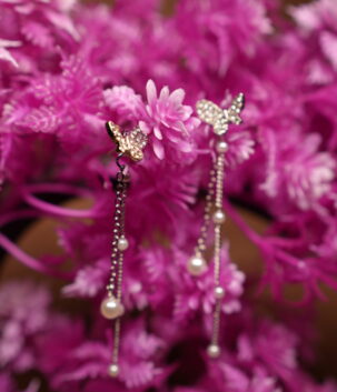 Crystal butterfly stud earrings with silver chain and faux pearl drops displayed on pink artificial flower tree – D2Dazzle fashion jewellery India