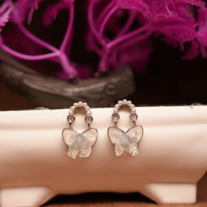 Silver pearl hoop earrings with clear crystal butterfly pendant drop displayed on white ceramic stand with pink flowers – D2Dazzle fashion jewellery India