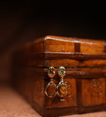 Gold floral stud earrings with tiger's eye teardrop stone pendant displayed on antique wooden jewellery box – D2Dazzle fashion jewellery India