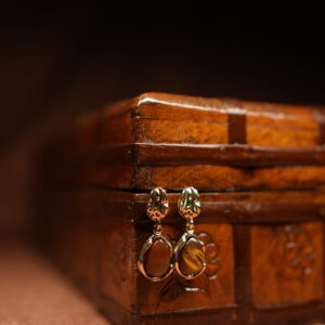 Gold floral stud earrings with tiger's eye teardrop stone pendant displayed on antique wooden jewellery box – D2Dazzle fashion jewellery India