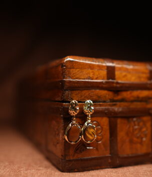 Gold floral stud earrings with tiger's eye teardrop stone pendant displayed on antique wooden jewellery box – D2Dazzle fashion jewellery India