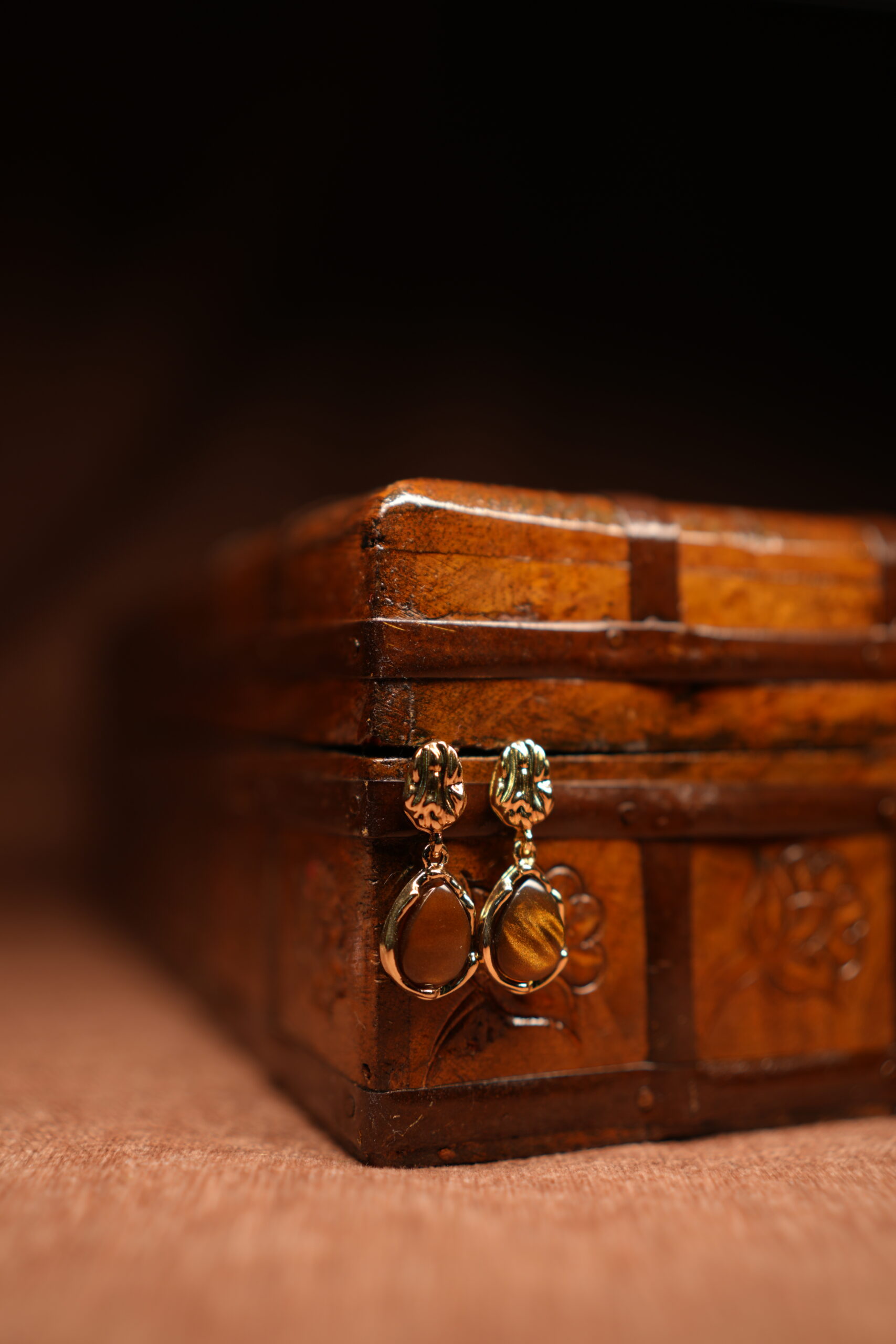 Gold floral stud earrings with tiger's eye teardrop stone pendant displayed on antique wooden jewellery box – D2Dazzle fashion jewellery India