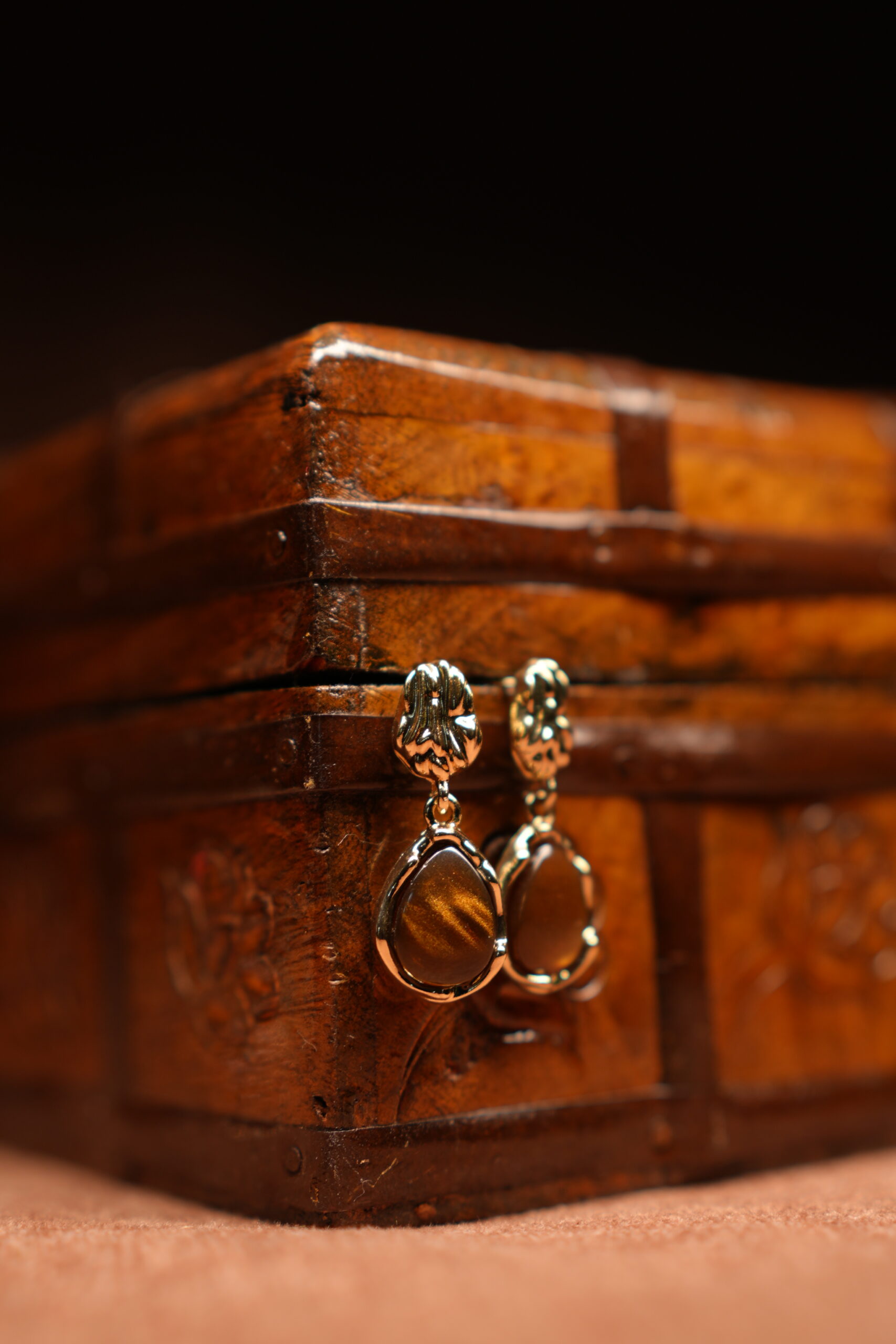 Gold floral stud earrings with tiger's eye teardrop stone pendant displayed on antique wooden jewellery box – D2Dazzle fashion jewellery India