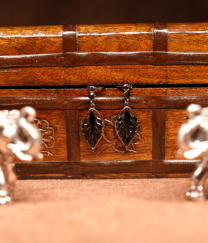 Silver filigree leaf drop earrings with black onyx stone centre displayed on wooden jewellery box – D2Dazzle fashion jewellery India
