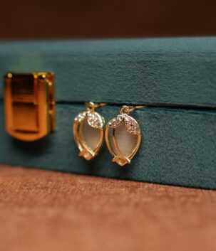 Gold tulip hook drop earrings with opalescent moonstone cabochon and crystal petal crown displayed on teal velvet jewellery box – D2Dazzle fashion jewellery India