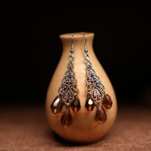 Silver filigree chandelier earrings with three amber crystal teardrop drops displayed on golden ceramic vase with dark background – D2Dazzle antique fashion jewellery India