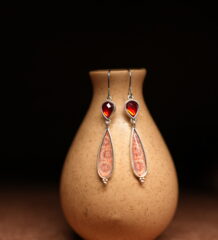 Silver hook dangle earrings with garnet red stone top and pink enamel teardrop pendant displayed on ceramic vase – D2Dazzle artisan fashion jewellery India