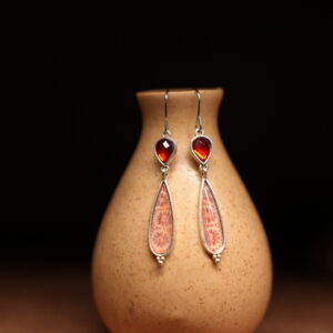 Silver hook dangle earrings with garnet red stone top and pink enamel teardrop pendant displayed on ceramic vase – D2Dazzle artisan fashion jewellery India