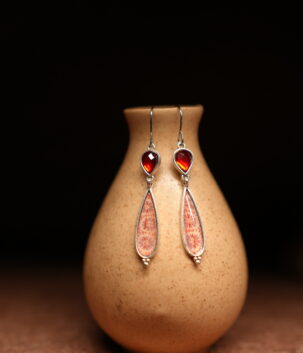 Silver hook dangle earrings with garnet red stone top and pink enamel teardrop pendant displayed on ceramic vase – D2Dazzle artisan fashion jewellery India