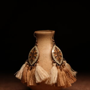 A pair of ivory and gold lotus enamel marquise-shaped drop earrings with five alternating ivory cream and champagne gold thread tassels, displayed on a speckled beige ceramic vase against a dark background.