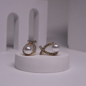 Gold-toned crystal wishbone pearl stud earrings displayed on a white cylindrical prop