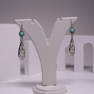 Oxidised silver-tone teardrop drop earrings with round turquoise stone and intricate filigree swirl design, displayed on a white earring stand