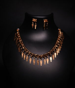 Antique gold plated necklace and earrings set with cascading leaf-shaped drops on a woven beaded chain, displayed on a black jewellery bust.