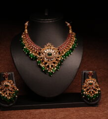 Gold plated kundan necklace set with floral motifs and deep blue beaded drops, paired with matching earrings on a black display bust