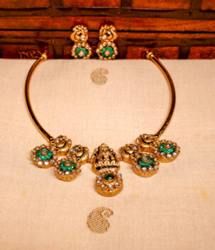 Antique kundan necklace set with peacock motifs and emerald green floral pendants, paired with matching peacock stud earrings.