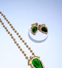 Gold plated antique-finish beaded necklace and stud earring set featuring a green enamelled paisley design bordered with sparkling white crystal stones, displayed on a white background.