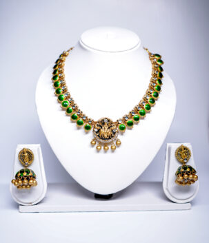 Gold plated temple-style necklace set with green kundan stones and a Goddess Lakshmi pendant, paired with matching jhumka earrings.
