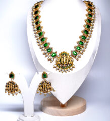 Gold plated temple jewellery set with green stone necklace, Goddess Lakshmi pendant, and matching jhumka earrings displayed on a mannequin.