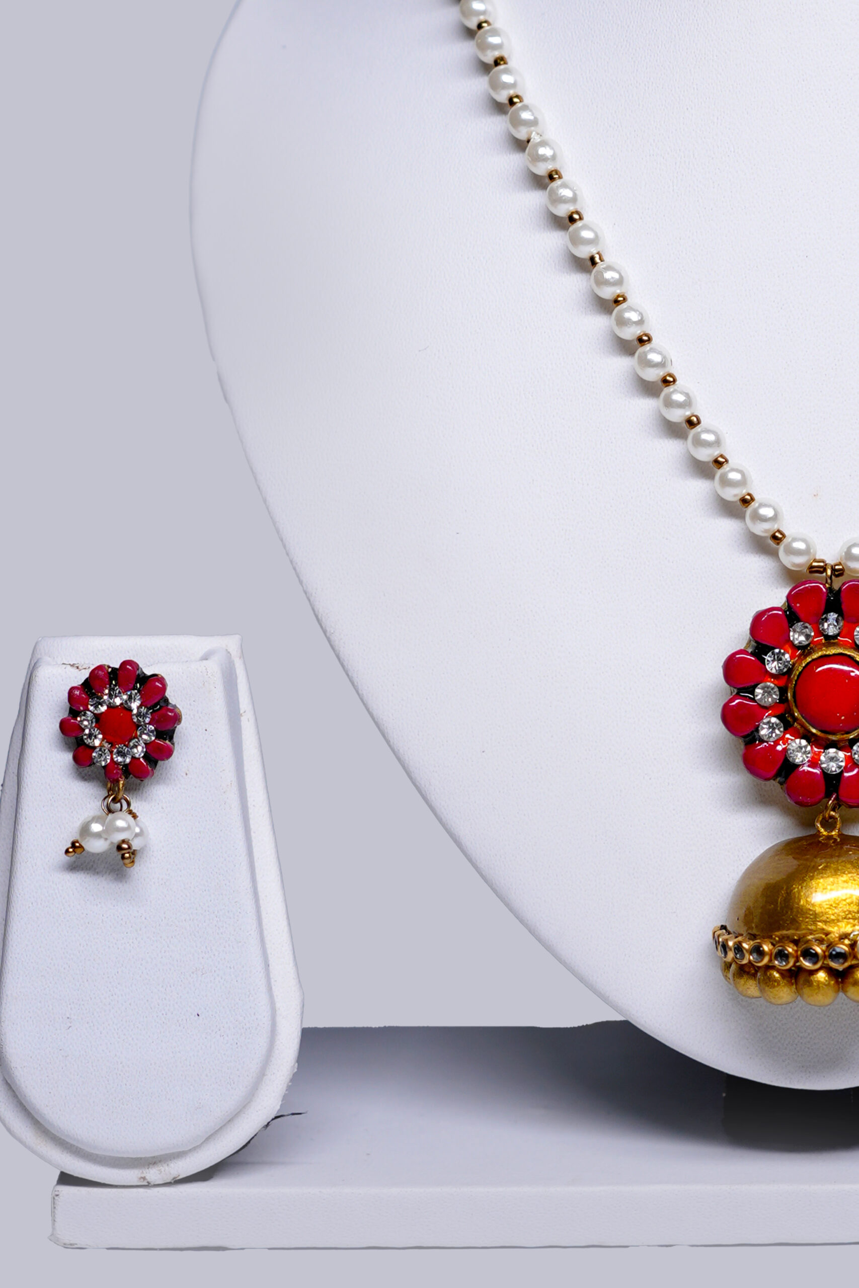 Close-up of coral-pink floral pendant with gold jhumka drop and sparkling stone detailing from the pearl necklace set by D2Dazzle.