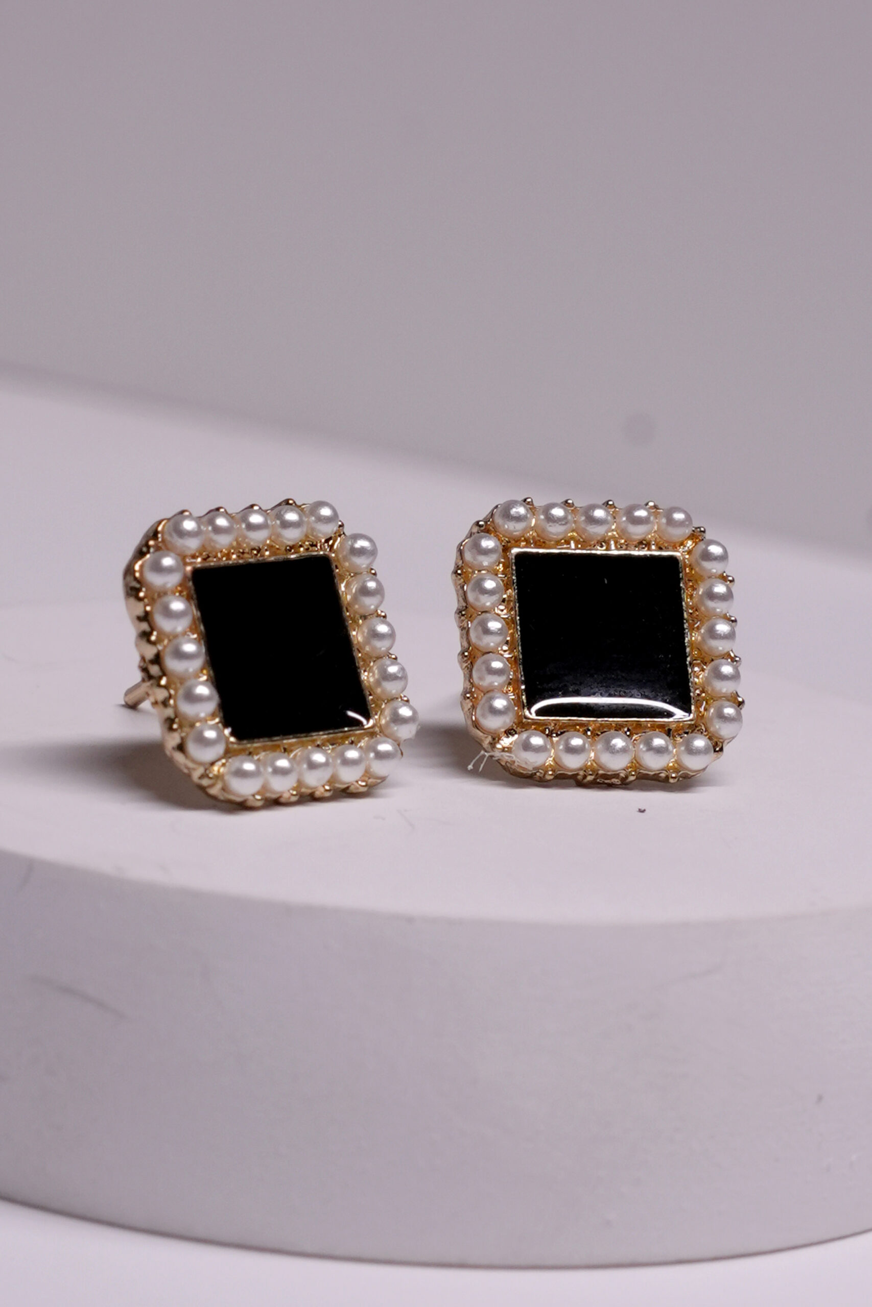 Close-up view of black onyx pearl stud earrings showing pearl border detailing and glossy onyx centre.