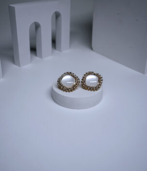 Gold plated pearl stud earrings with a sparkling crystal halo border, displayed on a white pedestal.