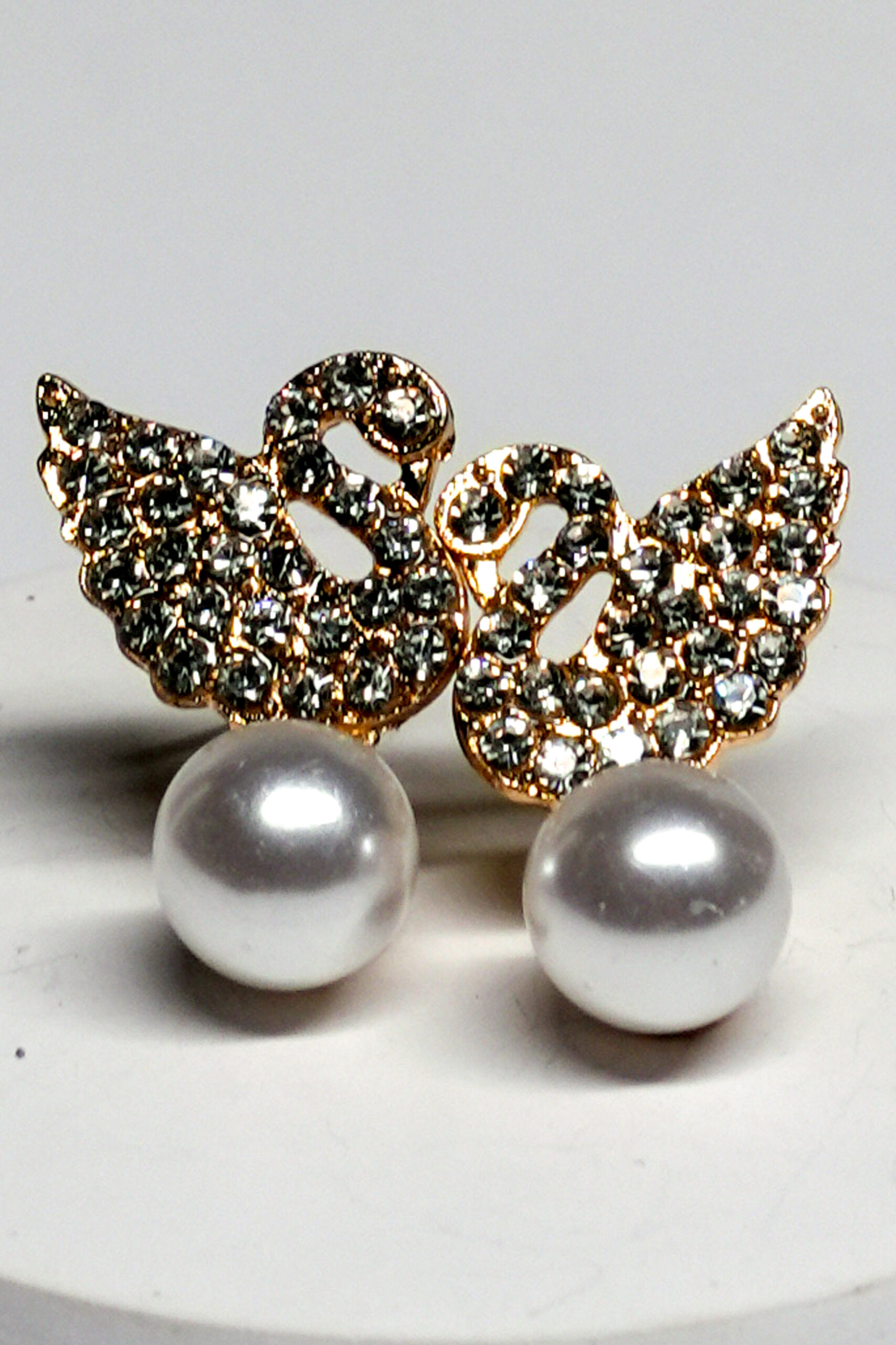 Close-up view of crystal swan pearl earrings showing swan detailing and pearl drop accent.