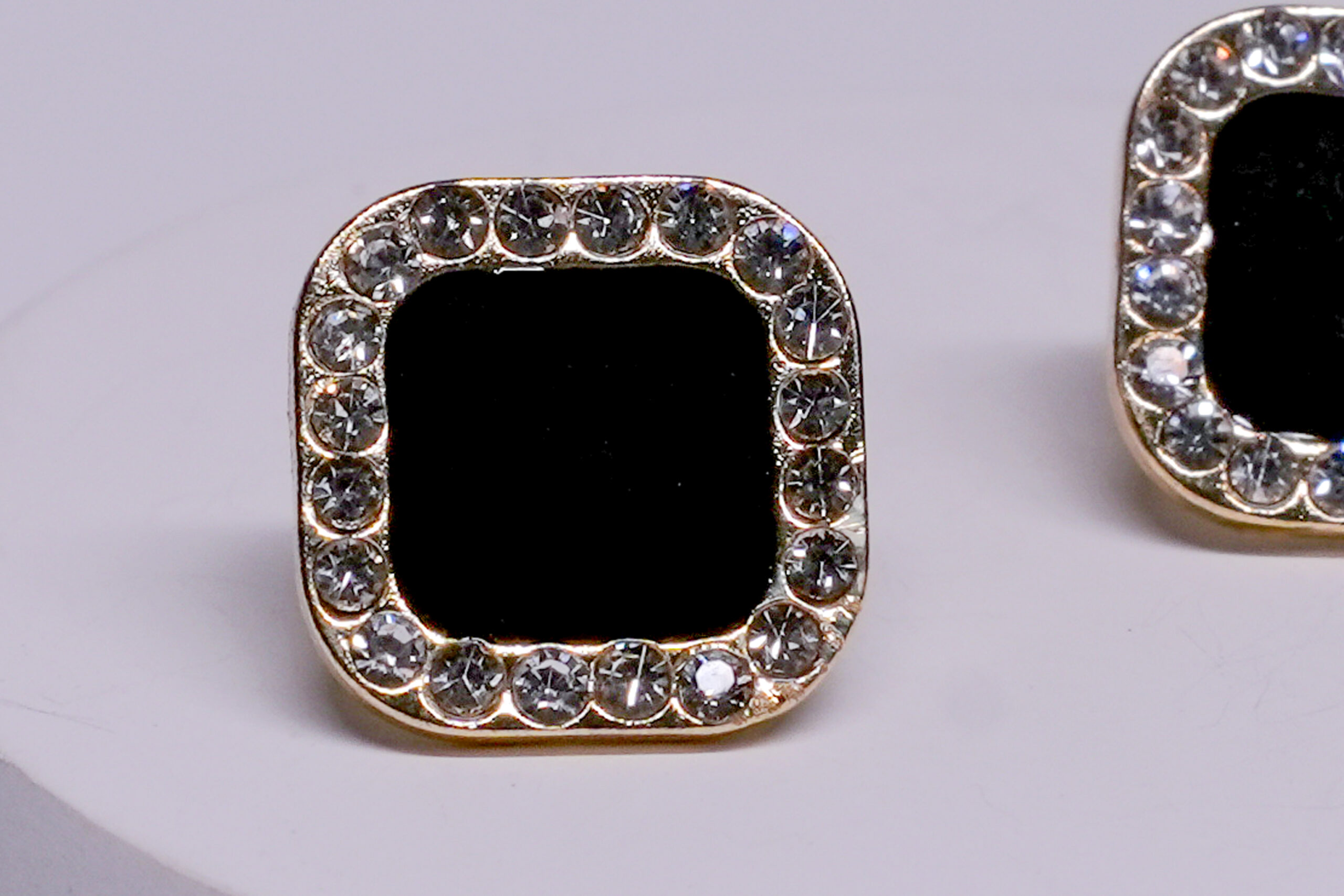 Close-up view of black onyx crystal stud earrings showing crystal border detailing and glossy onyx centre.