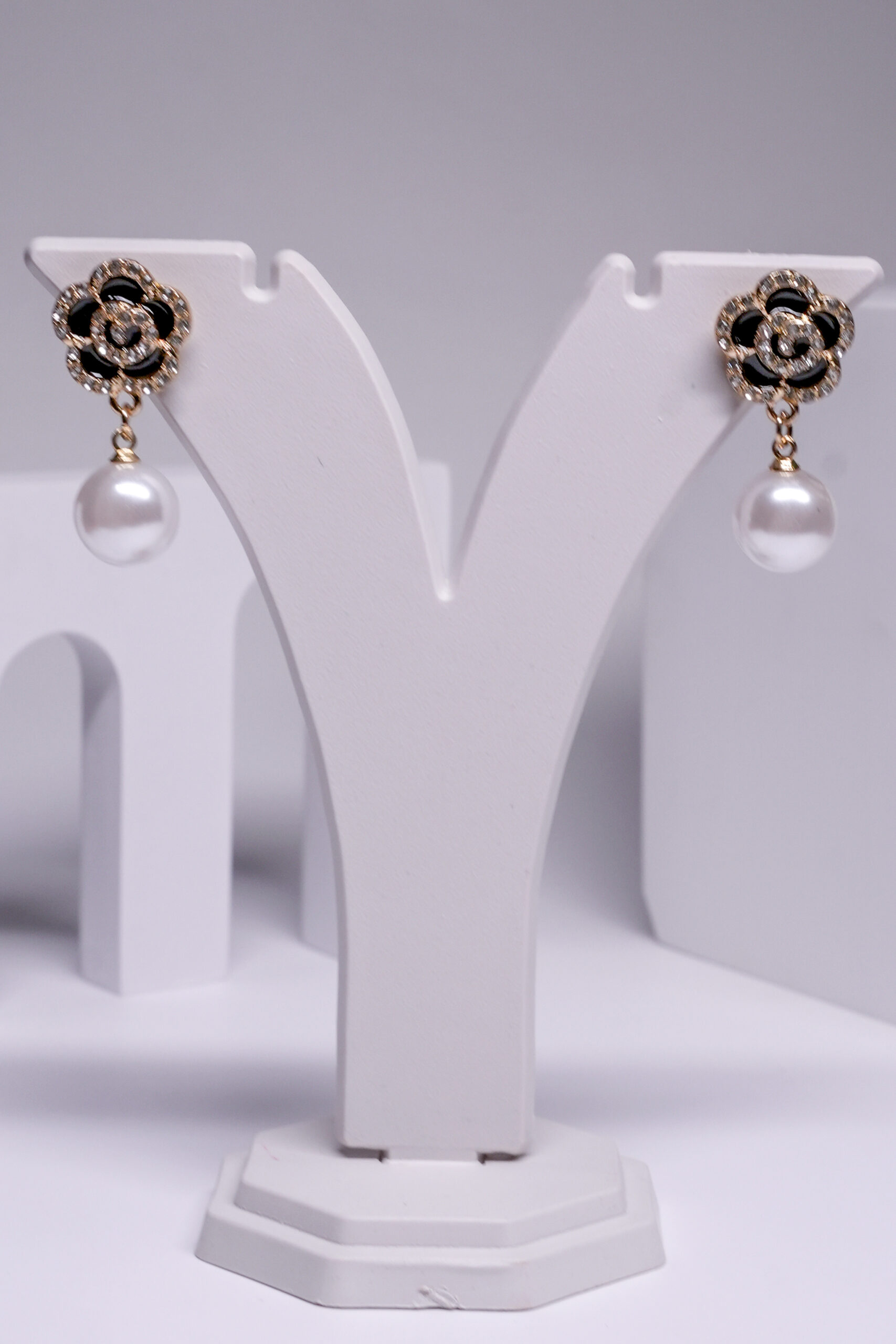 Close-up view of black floral crystal pearl earrings showing floral crystal detailing and hanging pearl drop.