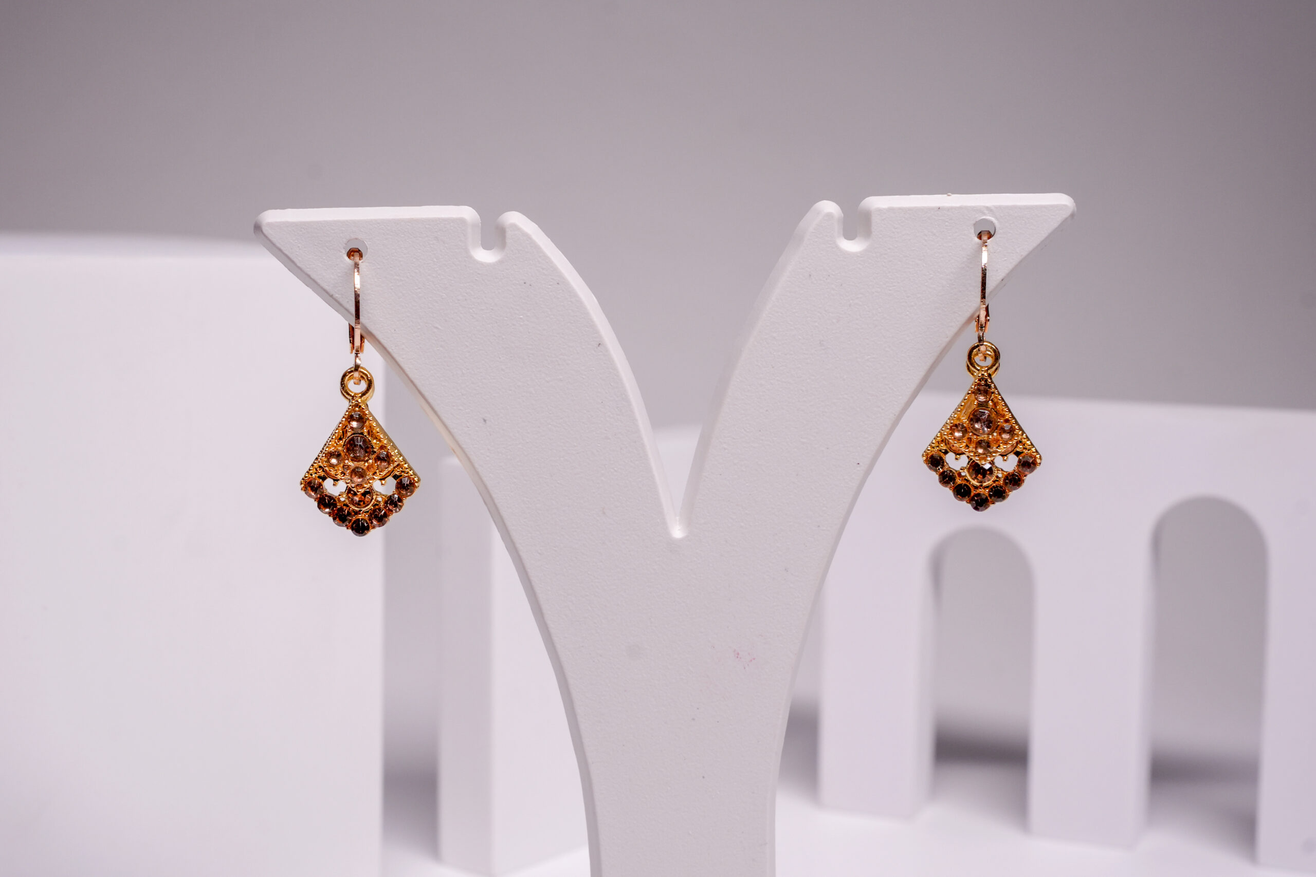 Close-up of gold plated topaz crystal earrings showing layered filigree design and stone detailing.