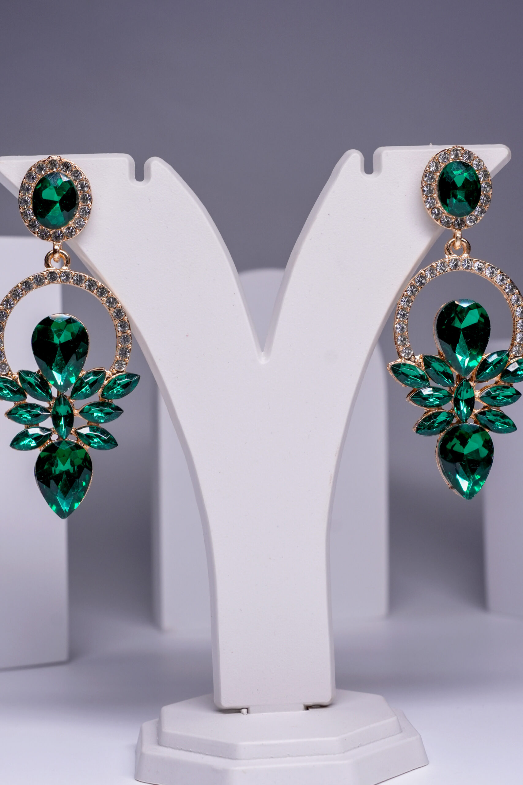 Close-up of gold plated emerald crystal earrings showing marquise and pear-shaped stone clusters.