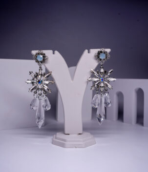 Silver plated opal crystal star drop earrings with faceted crystal drops, displayed on a white jewellery stand.
