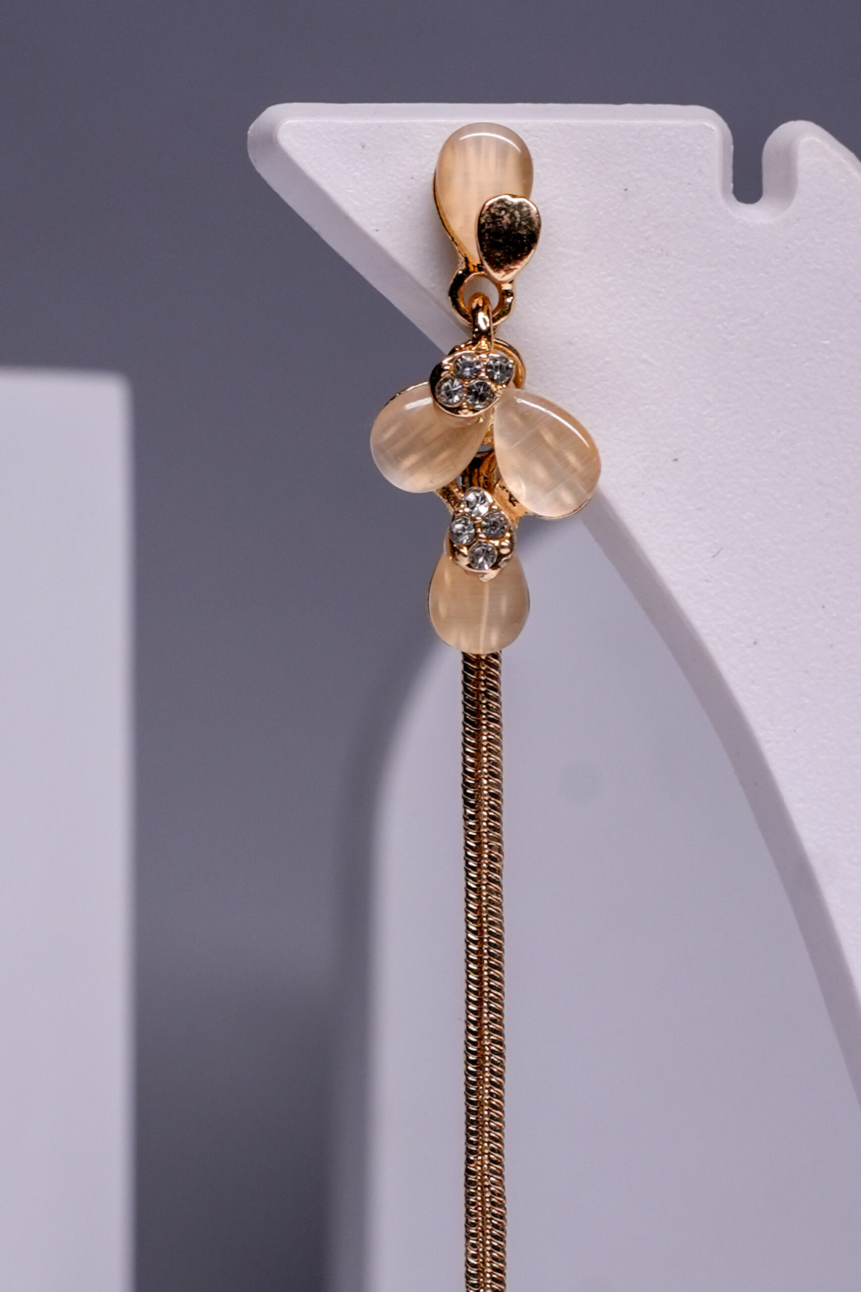 Close-up of gold plated floral earrings showing crystal accents and delicate chain tassel detailing.