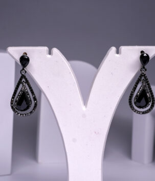 Black rhodium plated teardrop earrings with onyx stone and sparkling black crystal detailing, displayed on a white jewellery stand.