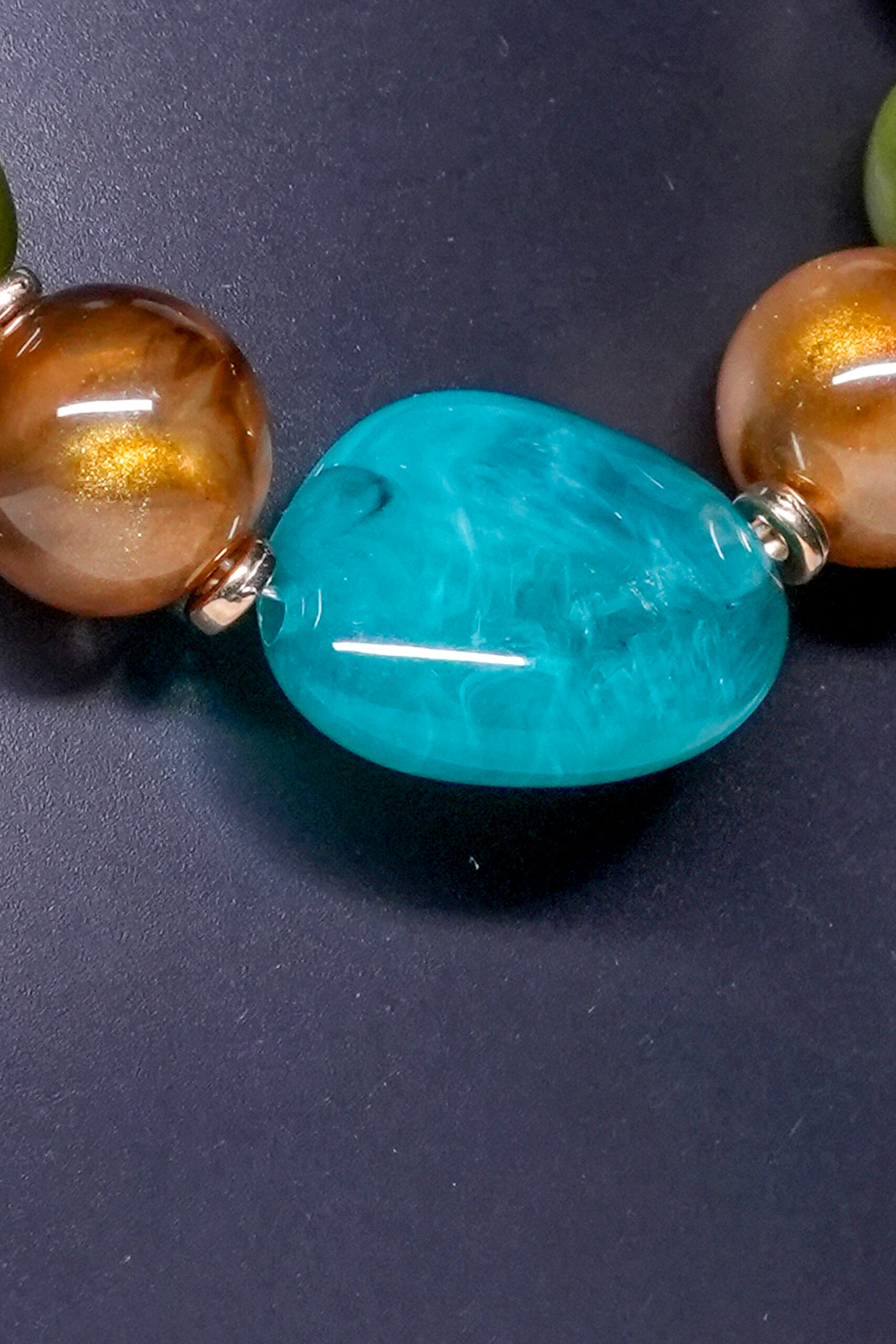 Close-up of handcrafted gemstone beaded statement necklace showing turquoise centrepiece and suede cord detail.