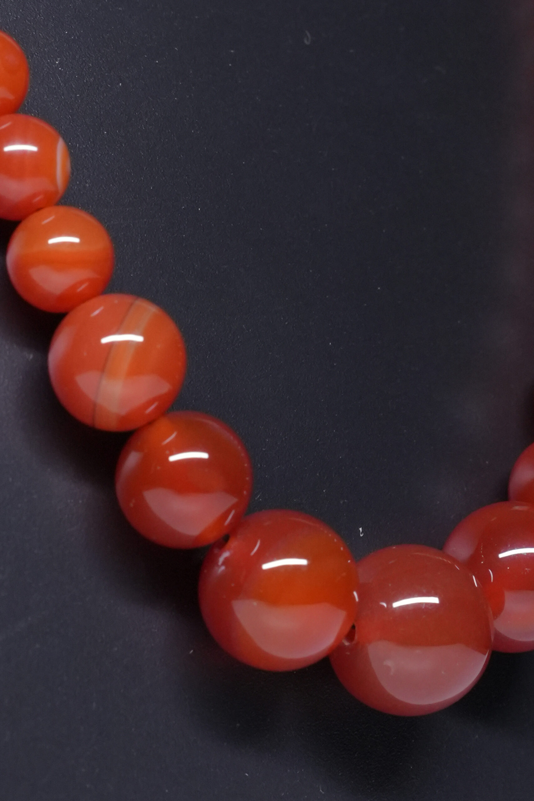 Close-up of natural carnelian beaded necklace showing graduated bead sizes and glossy stone finish.